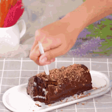 a person is cutting a piece of chocolate cake on a plate