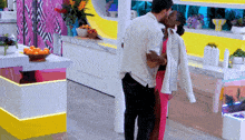 a man and woman are kissing in a kitchen with a bowl of oranges on the counter