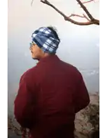 a man wearing a red jacket and a plaid headband looks out over a valley
