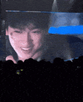 a man is smiling in front of a large screen in a dark room