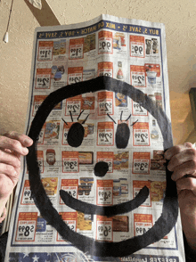 a person is holding a newspaper with a smiley face on it