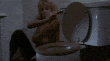 a person sitting in a toilet with the lid open