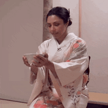 a woman wearing a kimono is holding a bowl