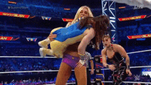 a woman is carrying a stuffed animal in a wrestling ring while another woman watches .