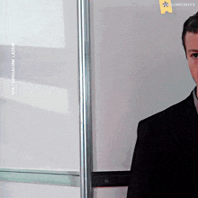 a man in a suit is standing in front of a white board with the words via sensacine latam on it