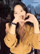 a woman in a yellow shirt is making a heart shape with her hands and the words eboforeoah are visible in the corner
