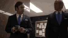 two men in suits and ties are standing next to each other .