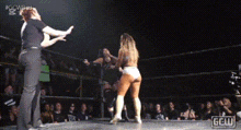 a woman is standing in a wrestling ring with a referee and another woman .