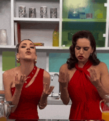 two women in red dresses are standing in a kitchen