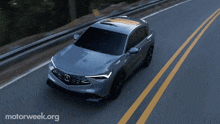 a grey car is driving down a highway with motorweek.org written on the bottom