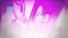 a woman looks at herself in a mirror with the letter m in the corner