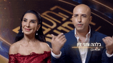 a man in a suit and a woman in a red dress are sitting next to each other in front of a sign that says luck