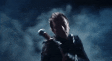 a man is holding a sword in his hand in a dark room with smoke coming out of it .