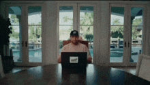 a man is sitting at a table using a laptop with a sticker on it that says ' craigslist '