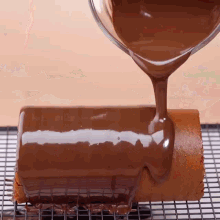 chocolate is being poured on a cake on a cooling rack