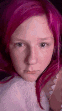 a girl with pink hair is making a funny face .