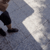 a person standing on a tiled floor with their shadow on the ground