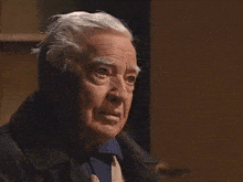 a man with gray hair and a blue shirt looks at something