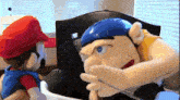 two stuffed animals , one of which is a mario character , are standing next to each other .