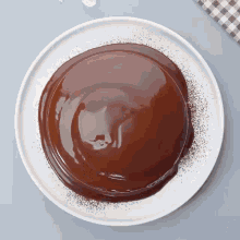 a white plate topped with a chocolate cake covered in chocolate sauce