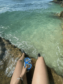a person sitting on a rock with their feet in the water