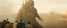 a group of people are standing in front of a statue of a monster .