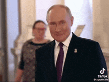 a man in a suit and tie is smiling in front of a woman in a dress .