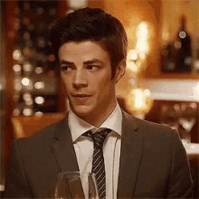 a man in a suit and tie is holding a glass of wine in his hand .