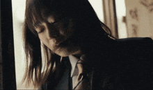 a woman in a suit and tie is looking out of a window