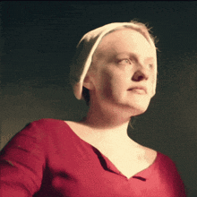 a woman wearing a red shirt and a white hat looks up