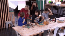 a group of people are sitting at a table eating food and drinking beer .