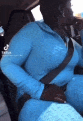 a woman in a blue outfit is sitting in the back seat of a car with a seat belt on .