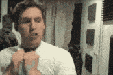 a man in a white shirt is adjusting his tie