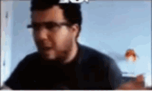 a man wearing glasses is sitting in front of a computer screen .