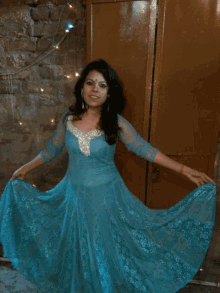a woman in a blue dress is smiling and holding a sparkler