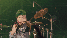 a man with green hair is singing into a microphone while wearing a shirt that says static shock