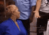 a woman in a blue robe is talking to a man in a white shirt .