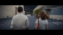 a man and a woman are walking down a street with a sign that says no parking