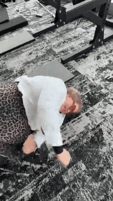 a person is laying on the floor in a gym with a leopard print shirt on .