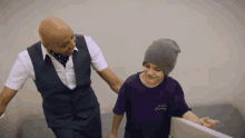 a young boy wearing a purple shirt with the word courage on it walks with a man