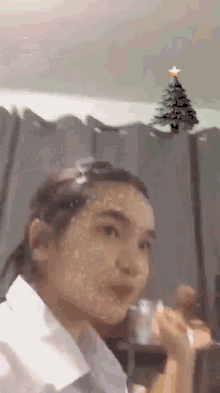 a girl with a christmas tree in the background .