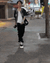 a man walking down a sidewalk wearing a jacket with the letter a on the front