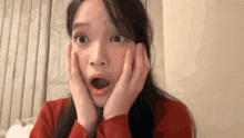 a woman in a red sweater is making a surprised face with her hands on her face