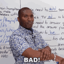 a man is standing in front of a white board with the word bad on it