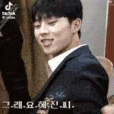 a man in a suit with braces on his teeth looks at the camera with a tiktok watermark above him