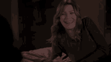 a woman is laughing while laying on a bed in a dark room .