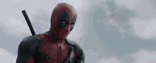 deadpool is wearing a superhero costume and holding a sword in front of a cloudy sky .