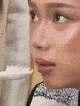 a close up of a woman holding a spoon in her mouth