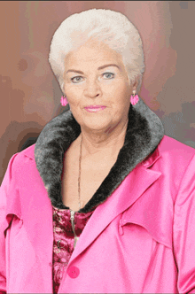 an elderly woman wearing a pink coat and earrings