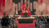 a crowd of people are watching a performance on a stage with a large k on the screen